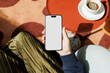 © Artem Podrez/Stocksy - Hand Holding Smartphone Mockup Coffee on Red Table