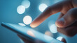 © Bonsales - Hand touching mobile phone screen with glowing bokeh background, interacting with digital technology and network connection
