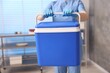 © New Africa - Laboratory worker holding blue cool box in clinic, closeup