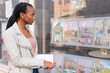 © Iryna - Woman looks at house listings in window during the day in the city
