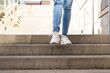© Iryna - Person walks up outdoor stairs wearing jeans and white shoes in a public area during daytime