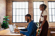 © BONNINSTUDIO/Stocksy - Colleagues collaborating on laptop in modern office space