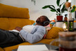 © Raul Navarro/Stocksy - Man relaxing on sofa enjoying music with headphones