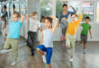 © JackF - Girls with boys repeat teaches sequences of movements during training, train to perform electro dance, enjoys active hobby to favorite music. Unrecognizable female teacher administer conduct class