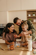 © La Famiglia - Happy family baking together, breaking eggs in kitchen