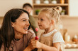 © La Famiglia - Happy mother daughter laughing enjoying lollipop at home