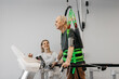 © wedmoments.stock - Elderly male patient in harness undergoing verticalization therapy with assistance from female therapist in modern rehabilitation facility with exercise equipment