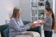 © New Africa - Little girl greeting her grandmother with gift and holiday card indoors