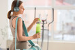 © Pixel-Shot - Sporty young woman with bottle of protein shake and headphones in gym