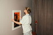 © Basil Pind/Stocksy - Woman Adjusting Picture Frame on Wall