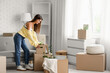 © Pixel-Shot - Young woman with cardboard boxes in rented apartment on moving day