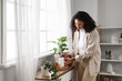 © Pixel-Shot - Young African-American woman with air humidifier and essential oils on commode in bedroom