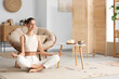 © Pixel-Shot - Young woman meditating on carpet at home
