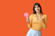 © Pixel-Shot - Young woman with mini fan on orange background