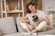 © Pixel-Shot - Young woman with cute pug dog sitting on sofa at home