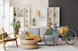 © Pixel-Shot - Interior of living room with grey sofa, shelving unit, houseplant and bicycle