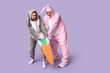 © Pixel-Shot - Beautiful young couple in bunny costume with paper carrot on purple background. Easter celebration