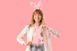 © Pixel-Shot - Young girl with Easter bunny ears and paper rabbit on pink background