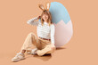 © Pixel-Shot - Young girl with Easter bunny ears and big paper egg on beige background
