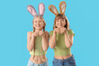 © Pixel-Shot - Cute young girls with Easter bunny ears on blue background
