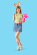 © Pixel-Shot - Young girl with Easter gift and bunny ears on blue background