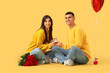 © Pixel-Shot - Young engaged couple with wedding ring and bouquet of roses on yellow background. Valentine's Day celebration