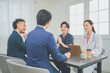 © HML - クリニックの会議室で打ち合わせをする若い医師とビジネスマン