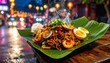 © NidNid - Steaming Asian Stir-Fried Noodles with Eggs and Seafood Served on a Banana Leaf at a Night Market
