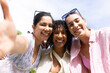© Wavebreak Media - Diverse female friends posing for selfie in park wearing sunglasses holding phone and light layers