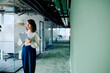 © we.bond.creations - Professional businesswoman using a digital tablet while moving through a sleek, modern office hallway, reflecting technology and dynamism