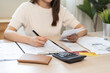 © KMPZZZ - Deduction planning, debt asian young woman calculating money balance of finance from bill and income, cost budget expenses for pay money form personal individual on table at home. Financial concept.