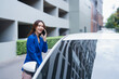 © Tj - Smiling businesswoman talking on a smartphone, standing next to a car, representing mobility, urban life, and modern professional communication during a commute or daily travel