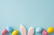 © ActionGP - Happy Easter greeting scene with pastel painted eggs and bunny ears arranged on a soft blue background conveying spring joy and festive decoration