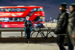 © Westend61 - Woman standing with bicycle by London bridge at night using smartphone