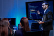 © ultramansk - A focused male AI solutions architect in a futuristic control hub debates generative AI applications collaborating on a complex machine learning model with his team under atmospheric blue lighting.