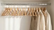 © Guzel - Row of wooden hangers on a metal rail inside a white minimalist closet with some shirts. Wardrobe organization, fashion retail, home interior.