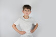 © Мар'ян Філь - A young boy in a white shirt stands with hands on hips, scowling and showing frustration, anger and defiance on gray background, conveying strong emotion and childhood temper