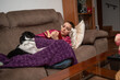 © C&A - Teenage girl reading book on sofa at home with her dog in cozy living room atmosphere