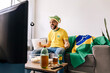 © kleberpicui - Brazilian football fan watching match at home while supporting national team. Emotional sports moment showing excitement, anticipation and entertainment lifestyle during televised competition.