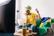 © kleberpicui - Brazilian football fan watching match at home while supporting national team. Emotional sports moment showing excitement, anticipation and entertainment lifestyle during televised competition.