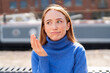 © Iryna - Young woman shows confusion while sitting by a dock in a city on a sunny day