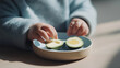 © Bonsales - Young child's hands exploring nutritious avocado and egg on a divided plate, promoting healthy eating and independent feeding