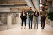 © Zoran Jesic - Diverse business team walking through modern office building