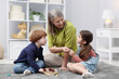 © New Africa - Nanny and cute little kids playing with wooden pieces on floor indoors