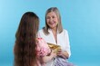 © New Africa - Little girl greeting her grandmother with gift on light blue background