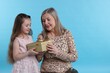 © New Africa - Little girl greeting her grandmother with gift on light blue background, space for text