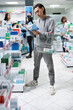 © DC Studio - Asian male shopper examines insomnia medications in neighborhood drugstore, reading instructions and ingredients. Young adult carefully pharmaceutical options to support better sleep.