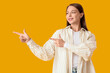 © Pixel-Shot - Beautiful happy young woman pointing at something on yellow background