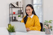 © David - Photo of joyful nice asian woman using laptop and smiling while sitting