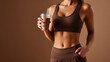 © PhotoLuxeStudio - Toned athletic woman with honey skin tone holding chocolate protein shake in plastic cup after workout
